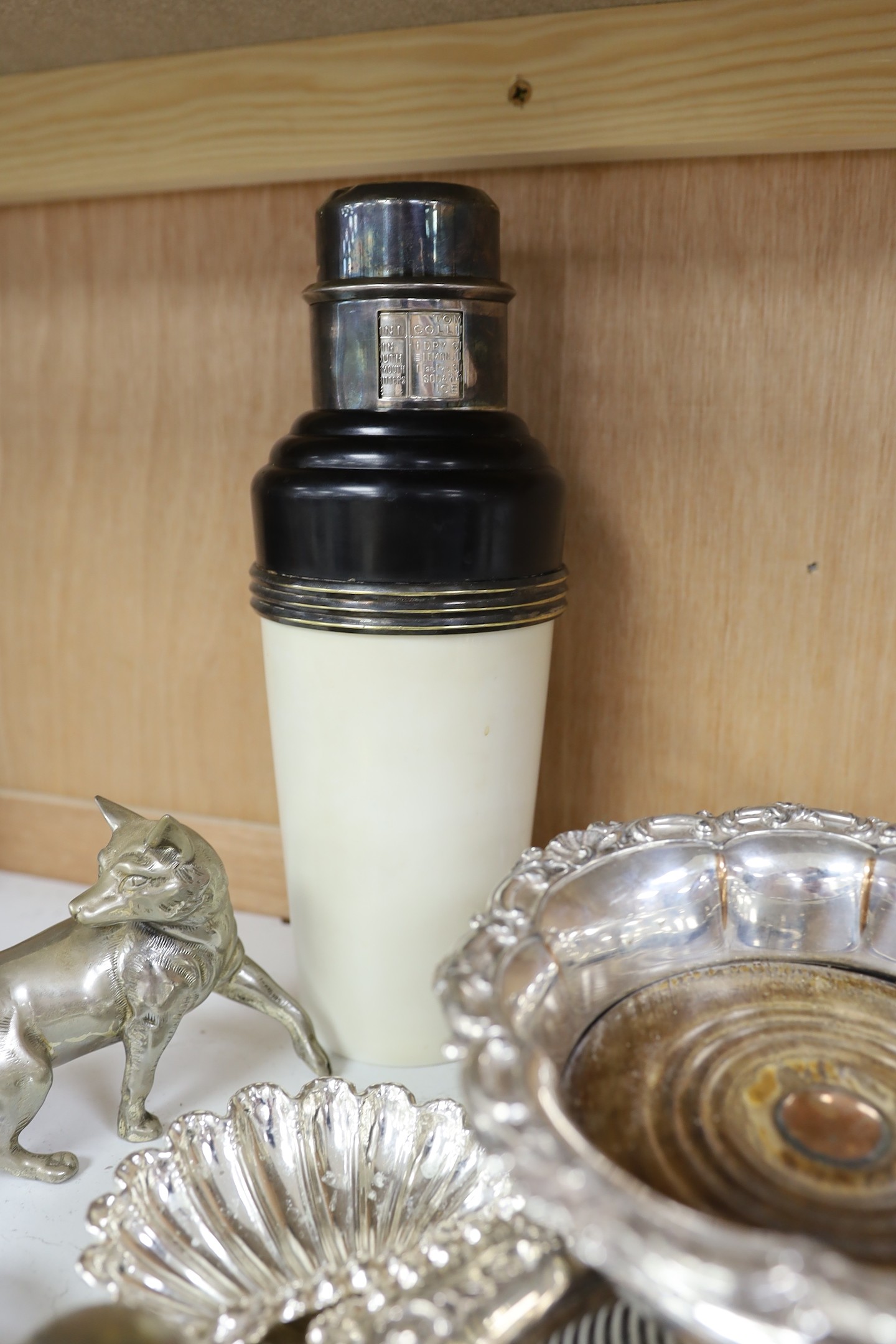 Three silver plated wine coasters, a pair of shell butter dishes, fox, ink well and a cocktail shaker